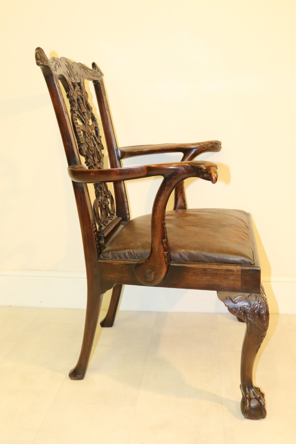 A late 19th-century Chippendale style mahogany armchair featuring carved eagle head terminals, a pierced back splat, brown leather seat, and cabriole legs with claw and ball feet. View XVIII
