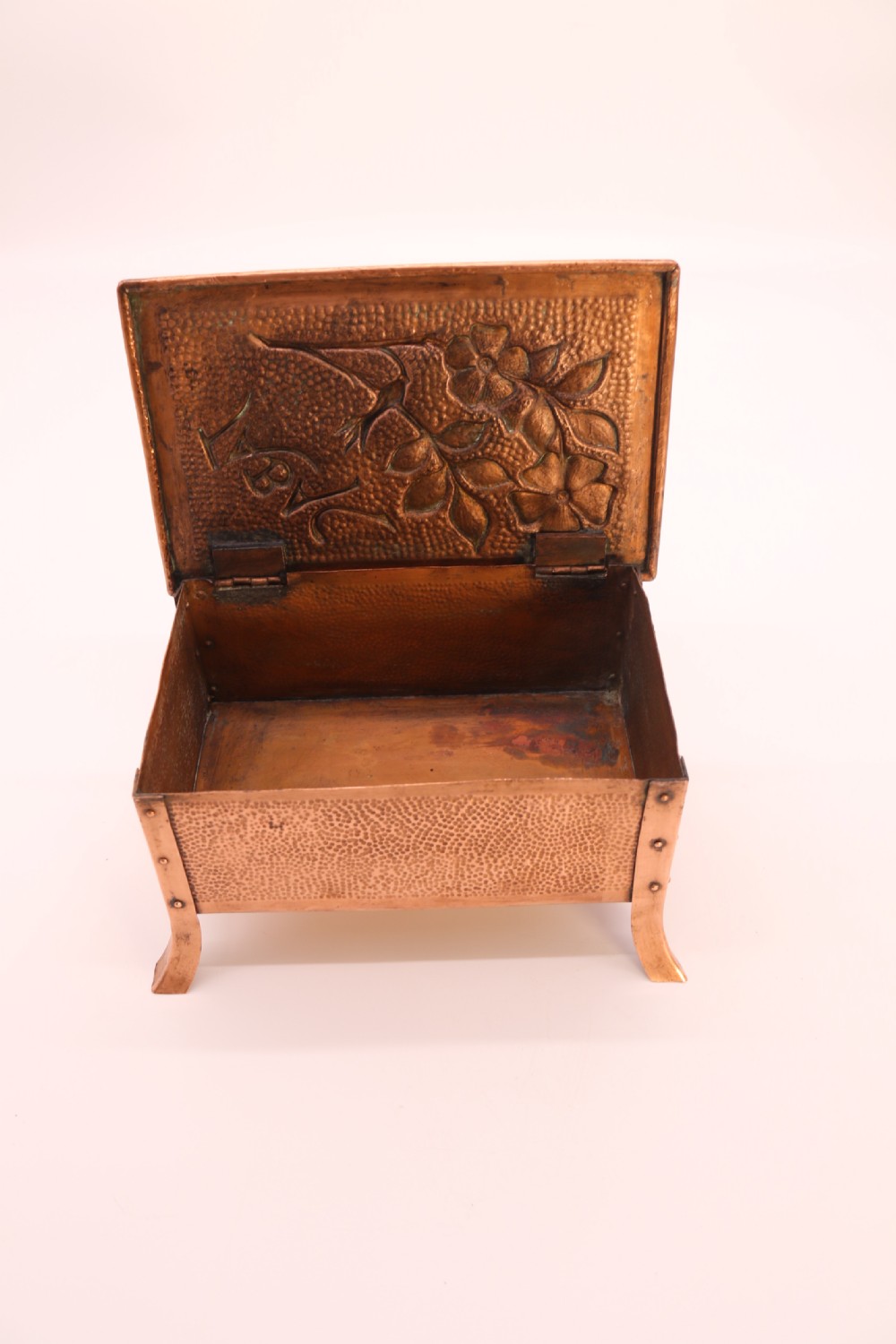 A rectangular Arts and Crafts copper box featuring a hand-hammered texture, splayed legs, and an embossed lid with a floral design and the word TABAC. View XI