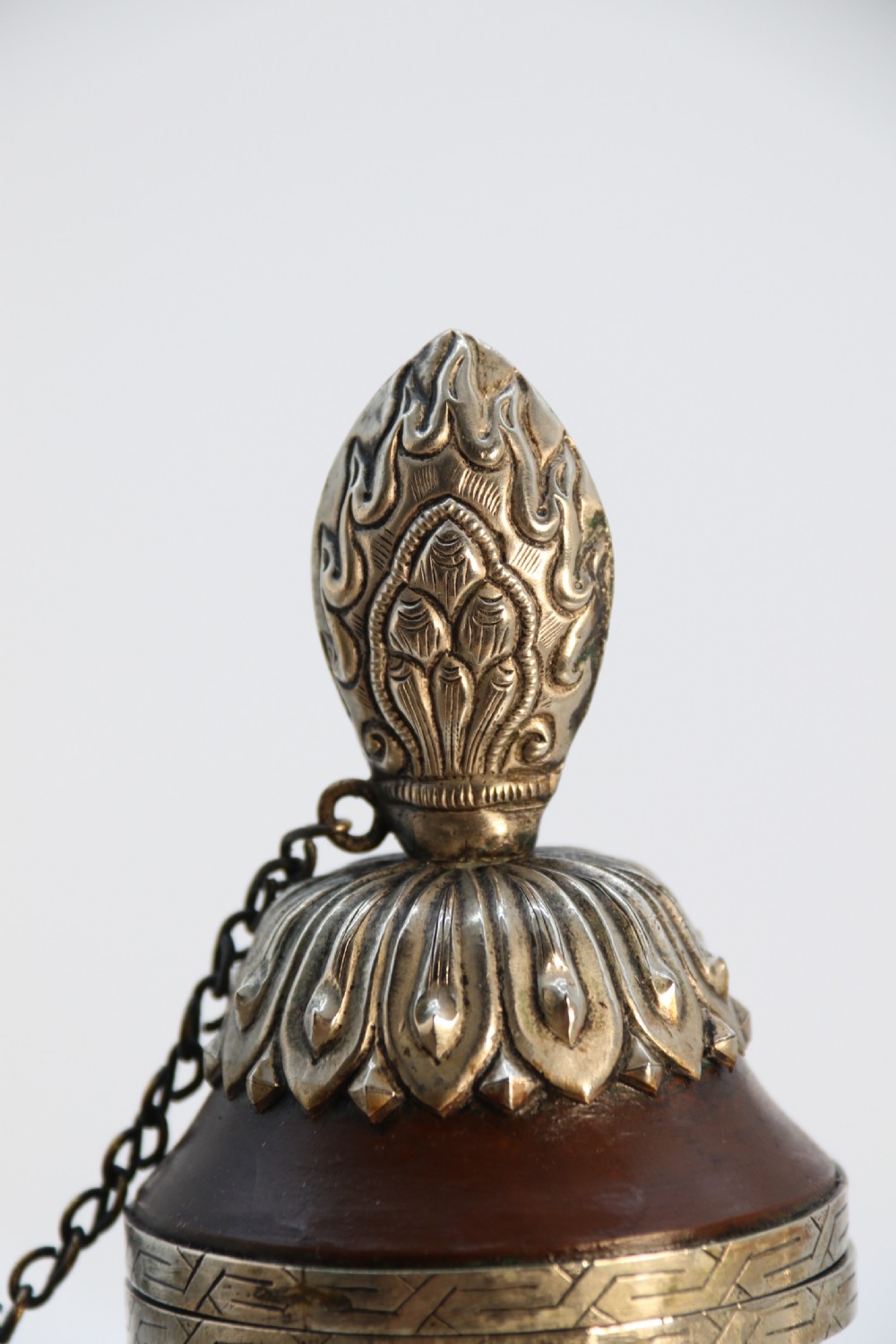 An antique Indo-Tibetan ritual ewer featuring a dark brown bulbous body, repousse silver dragon spout and handle, lotus base, and chained lid finial. View XI