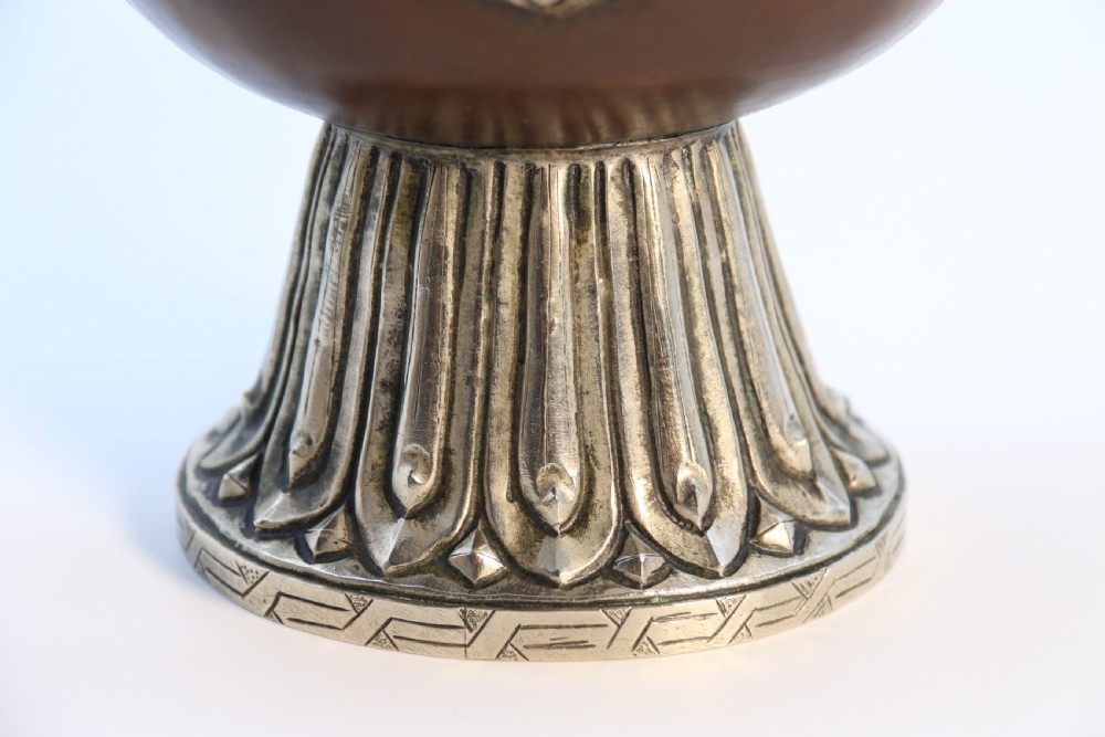 An antique Indo-Tibetan ritual ewer featuring a dark brown bulbous body, repousse silver dragon spout and handle, lotus base, and chained lid finial. View XIII