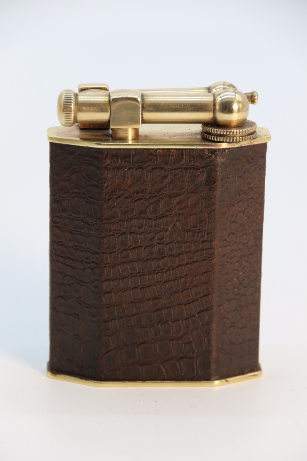 An Art Deco table lighter featuring a brown crocodile-embossed leather body with a solid brass base and upper lift-arm mechanism. View VII