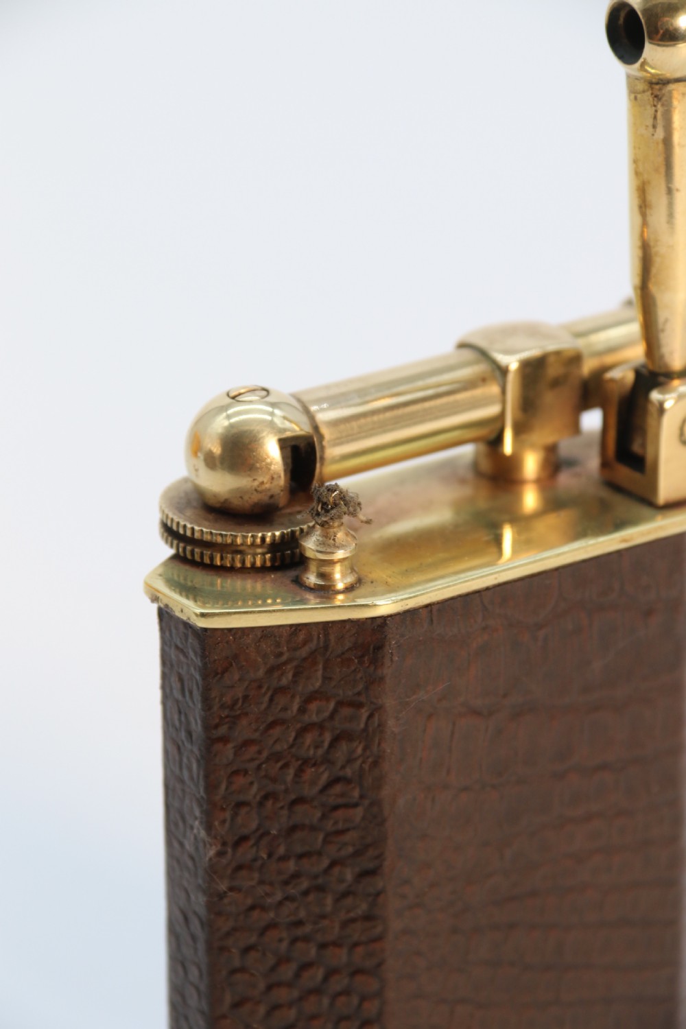 An Art Deco table lighter featuring a brown crocodile-embossed leather body with a solid brass base and upper lift-arm mechanism. View XIV