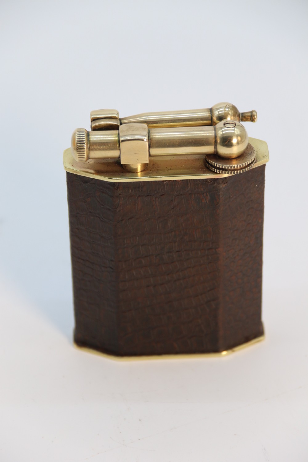 An Art Deco table lighter featuring a brown crocodile-embossed leather body with a solid brass base and upper lift-arm mechanism. View XV