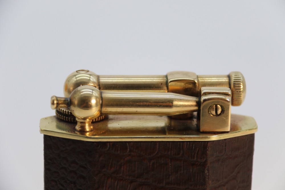 An Art Deco table lighter featuring a brown crocodile-embossed leather body with a solid brass base and upper lift-arm mechanism. View XVIII