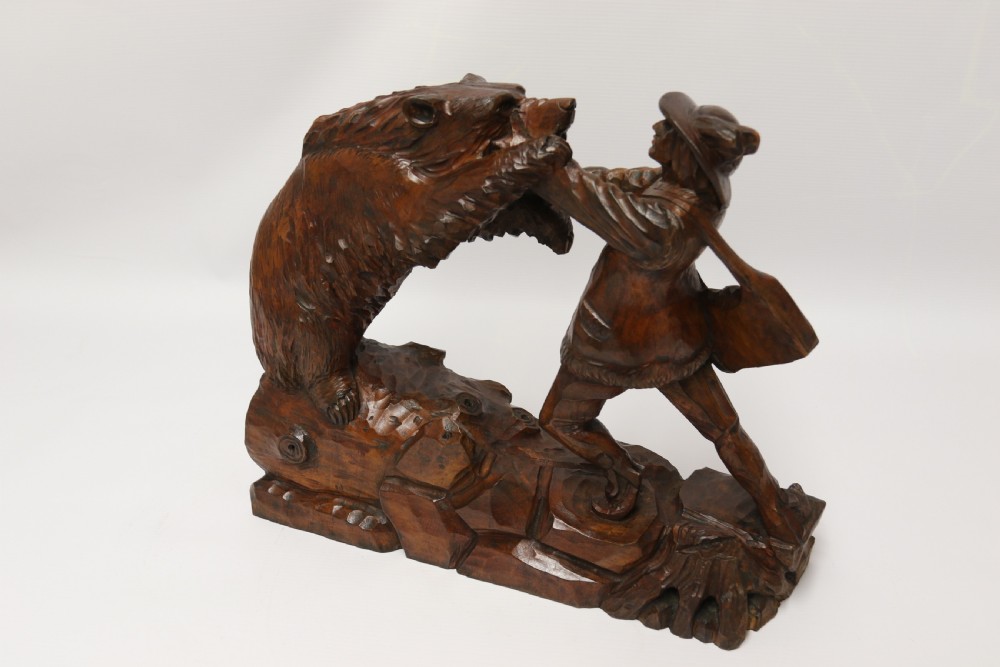 A late 19th-century carved wooden figure group depicting a huntsman battling a rearing bear on a log-form base. View XVIII