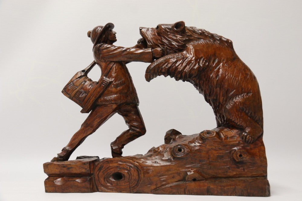 A late 19th-century carved wooden figure group depicting a huntsman battling a rearing bear on a log-form base. View XX