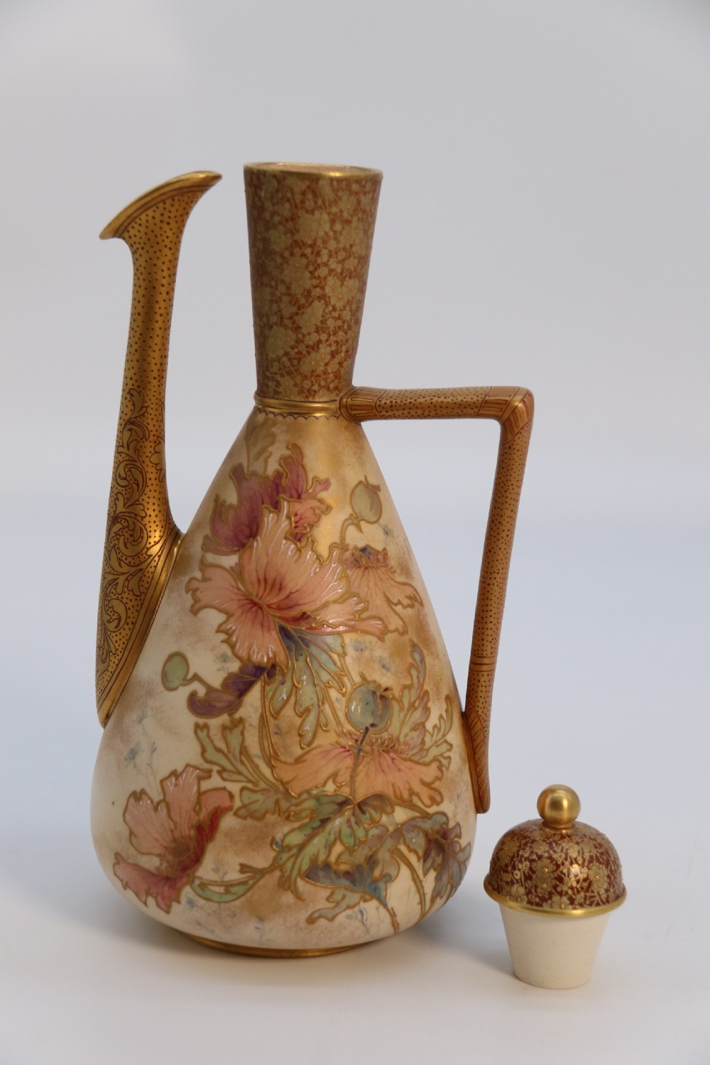 A late 19th-century Doulton Burslem ceramic ewer featuring hand-painted pink floral motifs, an elongated gilt spout, stippled gold handle, and matching stopper. View XIX