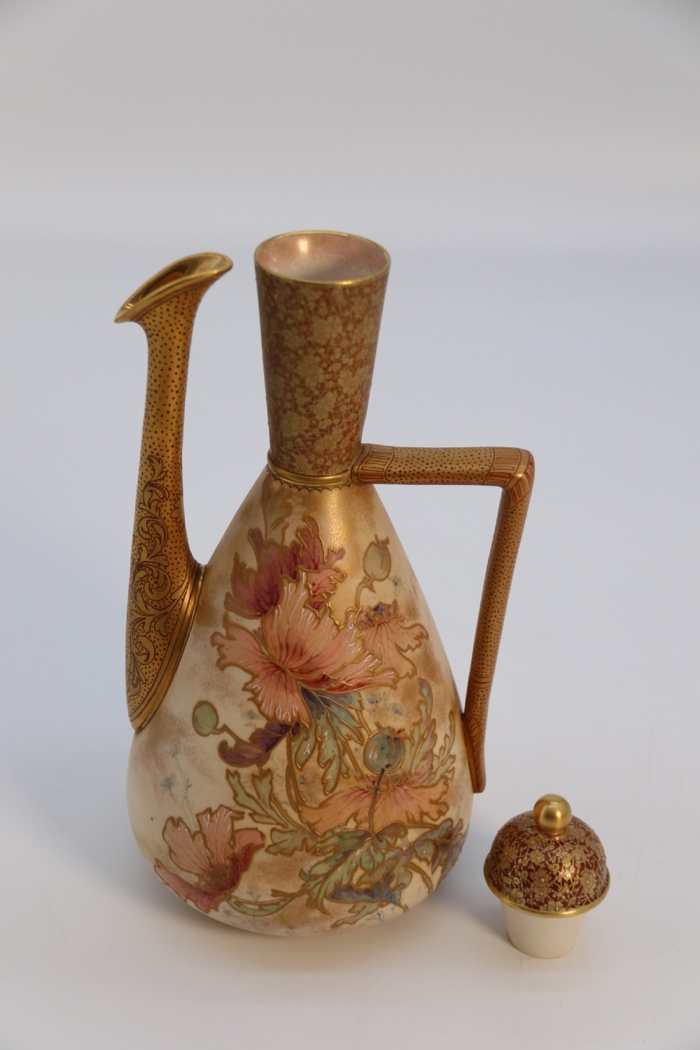 A late 19th-century Doulton Burslem ceramic ewer featuring hand-painted pink floral motifs, an elongated gilt spout, stippled gold handle, and matching stopper. View XX
