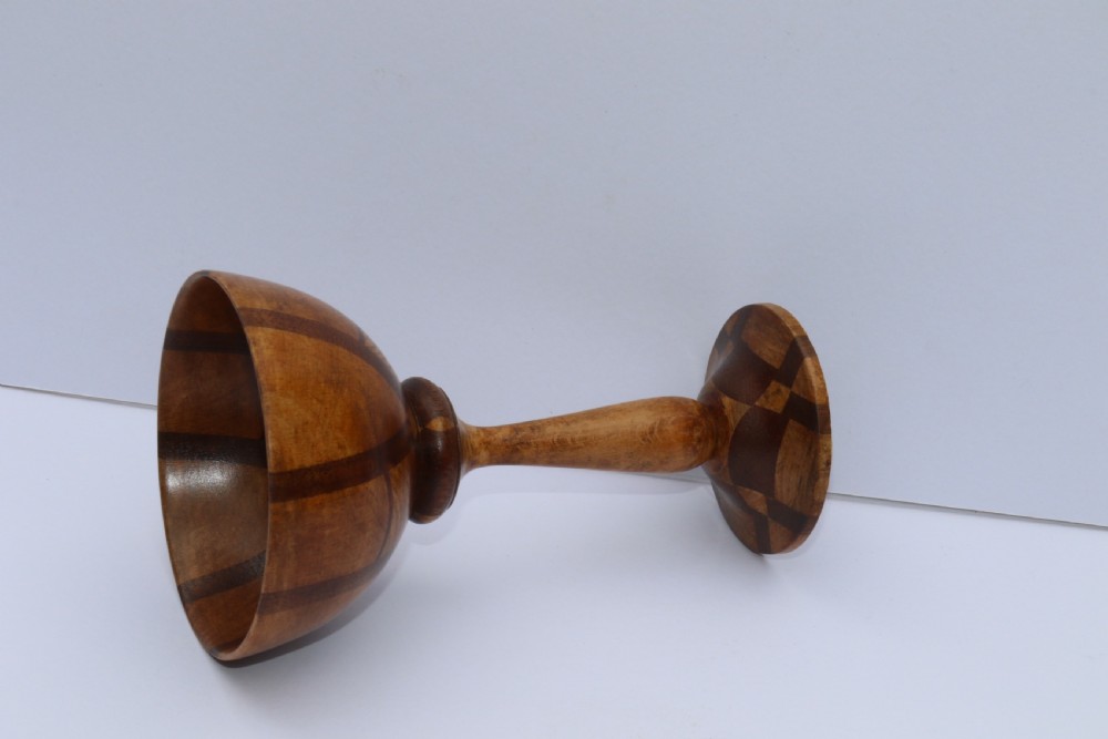A turned wooden goblet crafted from contrasting specimen woods with a flared rim, a slender stem, and a round patterned base. View III