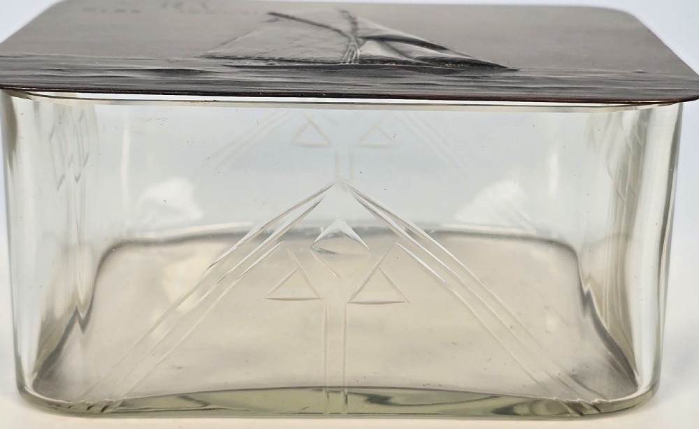 A clear glass rectangular box with a patinated bronze lid featuring a raised relief depiction of a sailing boat. View VIII