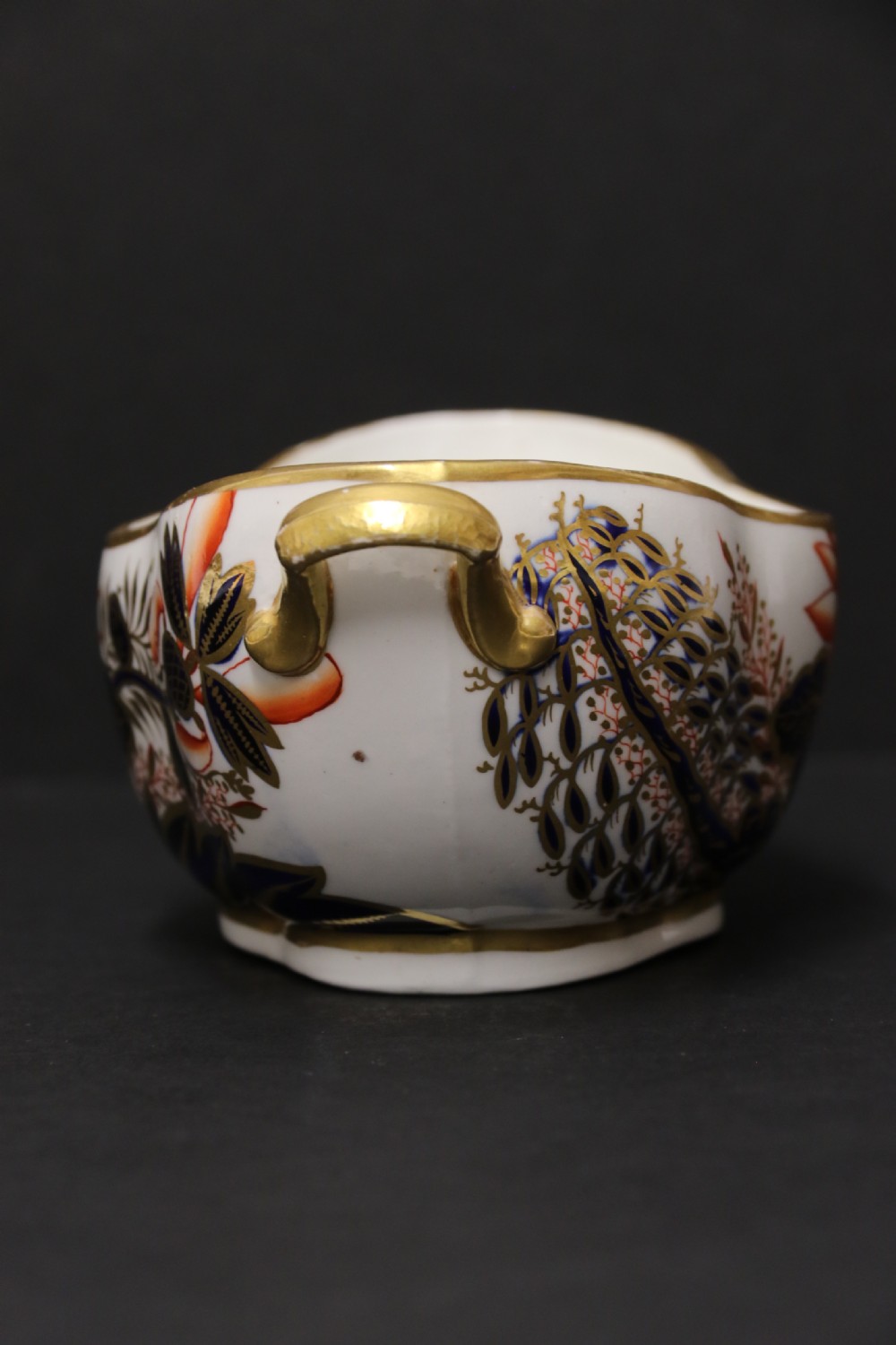 An early nineteenth-century boat-shaped white porcelain shallow dish with gilded side handles, decorated in hand-painted Imari floral motifs in cobalt blue, iron red, and gold. View V