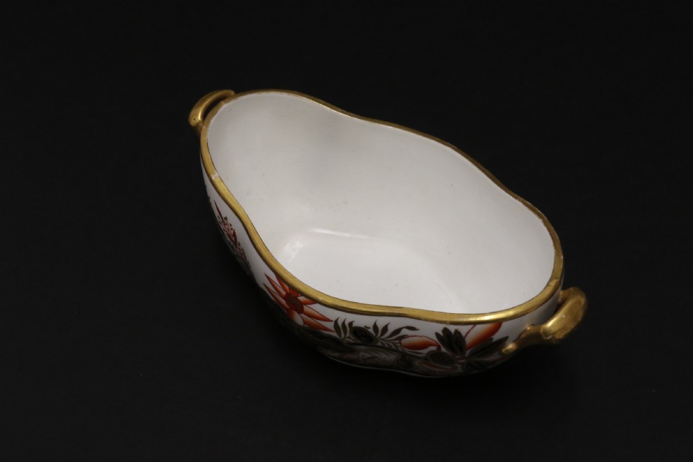 An early nineteenth-century boat-shaped white porcelain shallow dish with gilded side handles, decorated in hand-painted Imari floral motifs in cobalt blue, iron red, and gold. View VII