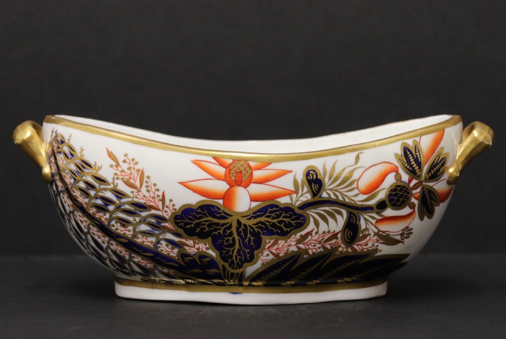 An early nineteenth-century boat-shaped white porcelain shallow dish with gilded side handles, decorated in hand-painted Imari floral motifs in cobalt blue, iron red, and gold. View X