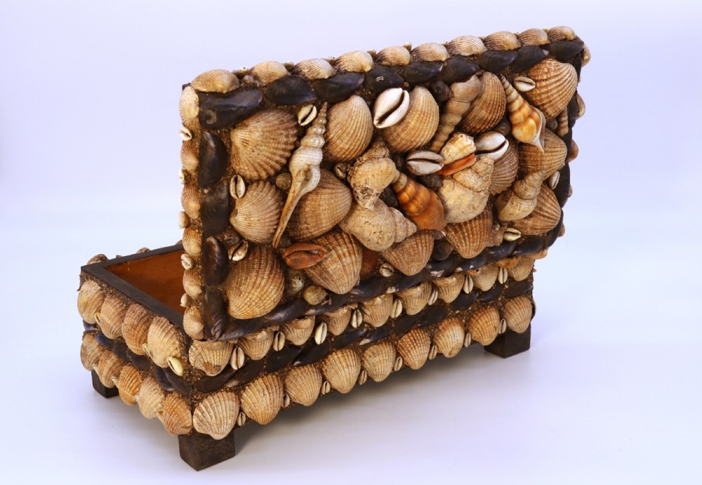 A rectangular folk art box raised on four small feet, fully encrusted with an intricate mosaic of natural sea shells including cockles, cowries, and mussels. View XVII