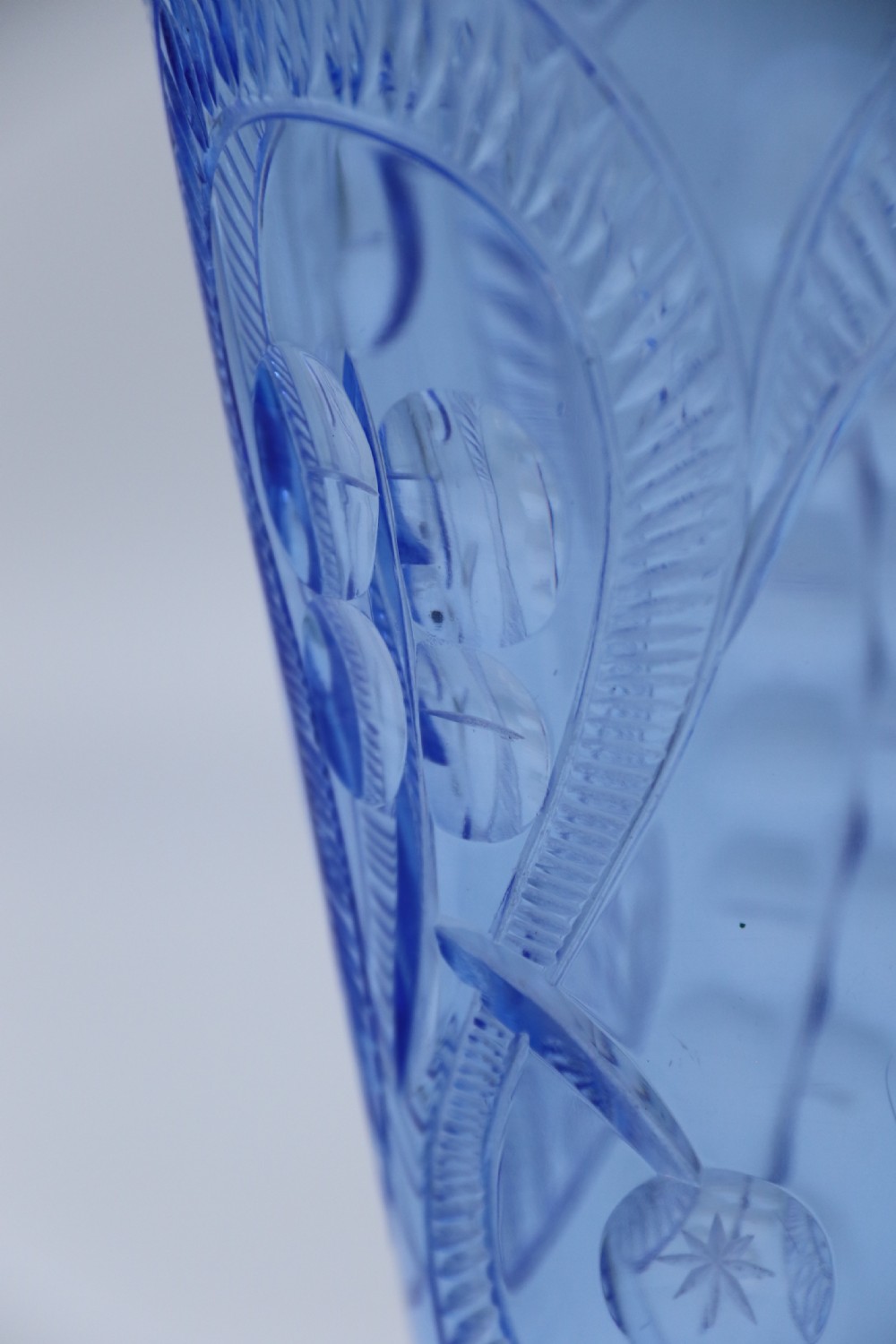 A flared Art Deco sapphire blue cut glass vase featuring geometric carved details on a faceted bulbous pedestal base. View VI