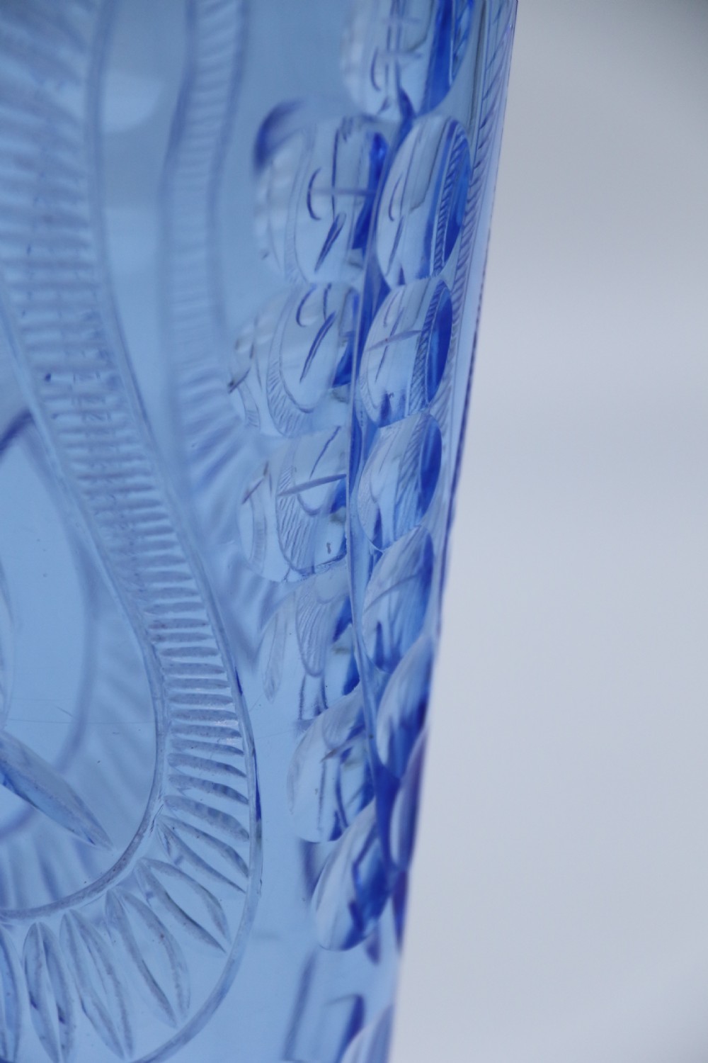 A flared Art Deco sapphire blue cut glass vase featuring geometric carved details on a faceted bulbous pedestal base. View X