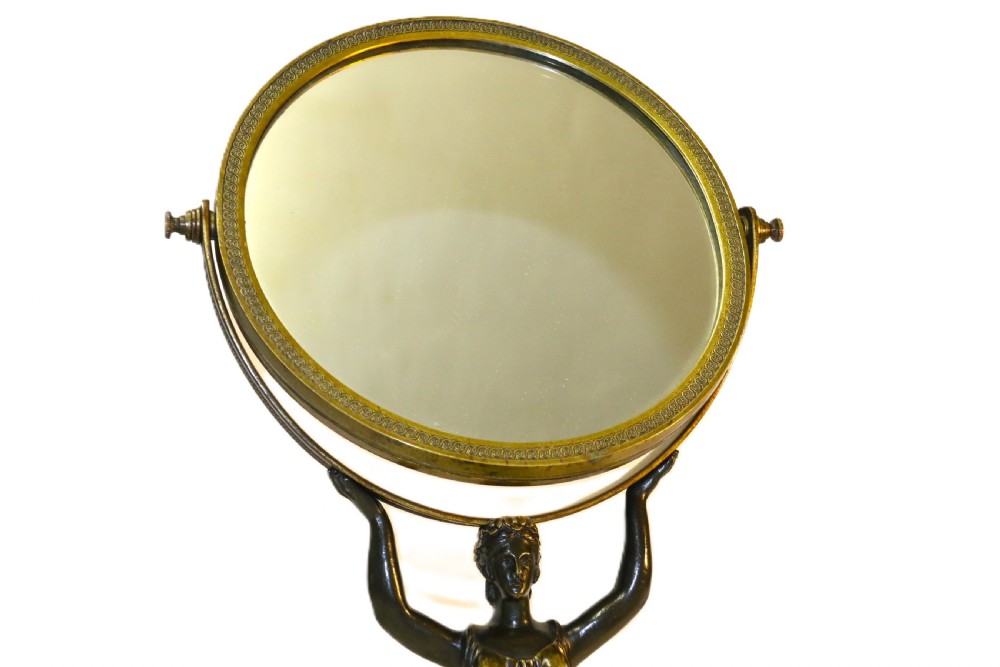 A French Empire period pedestal mirror featuring a patinated bronze classical female caryatid holding a circular tilting mirror with a gilt bronze bezel and base. View VII