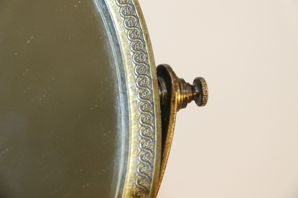 A French Empire period pedestal mirror featuring a patinated bronze classical female caryatid holding a circular tilting mirror with a gilt bronze bezel and base. View XII