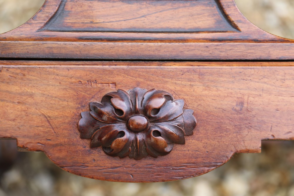 An early 19th-century flame mahogany library table featuring floral marquetry top borders, two frieze drawers with brass knobs, and carved trestle legs connected by a turned stretcher. View XI