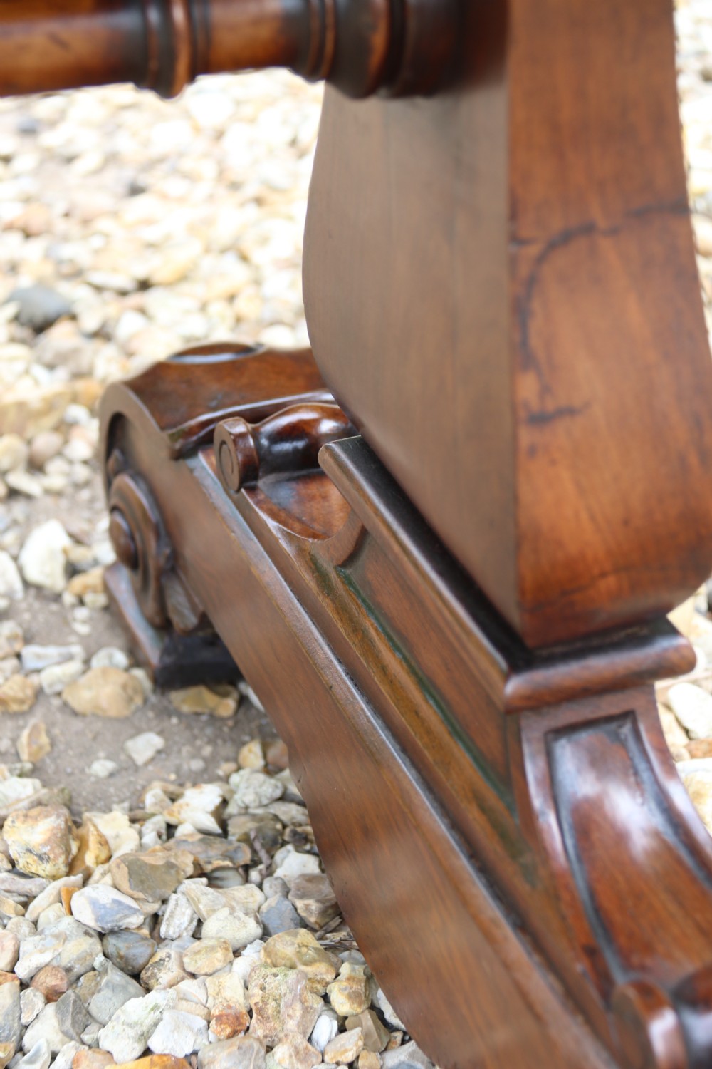An early 19th-century flame mahogany library table featuring floral marquetry top borders, two frieze drawers with brass knobs, and carved trestle legs connected by a turned stretcher. View XXI