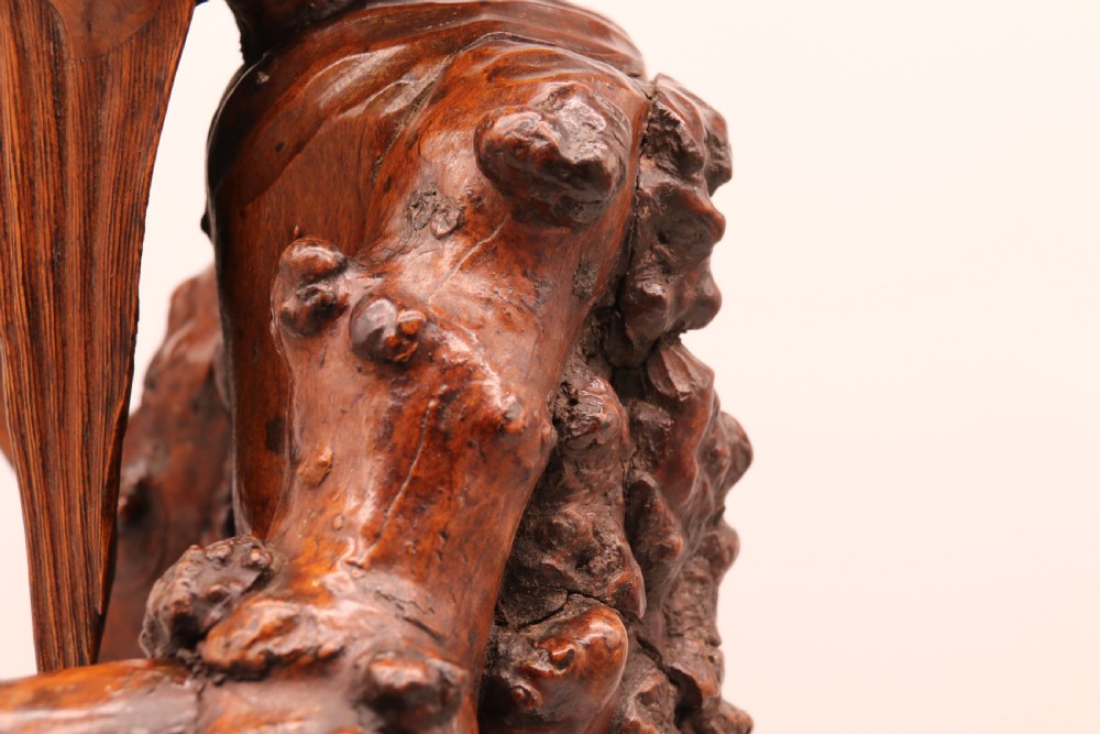 A late 19th-century Chinese carved burr root wood figure depicting a bearded scholar holding a staff, set upon a carved wood base. View XIX