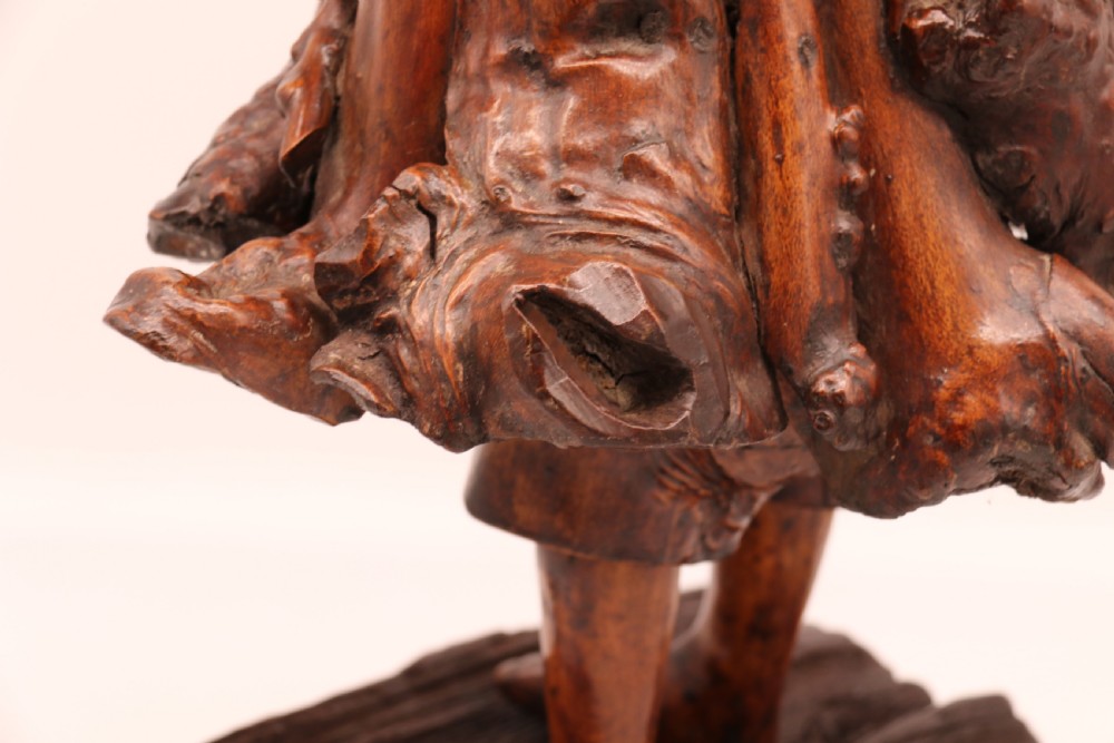 A late 19th-century Chinese carved burr root wood figure depicting a bearded scholar holding a staff, set upon a carved wood base. View XXI