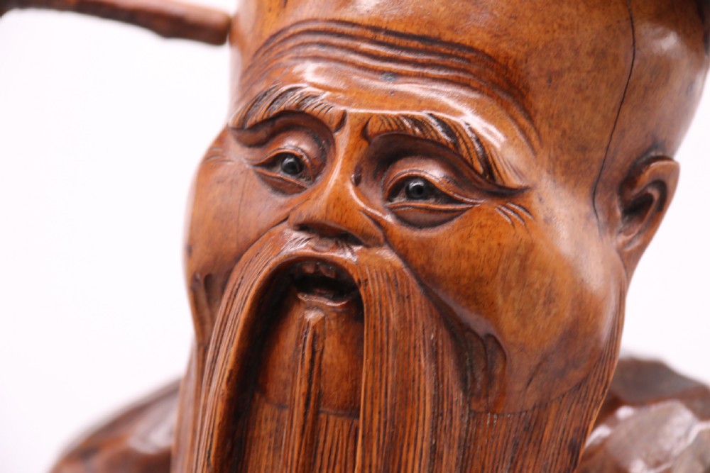 A late 19th-century Chinese carved burr root wood figure depicting a bearded scholar holding a staff, set upon a carved wood base. View XXIX