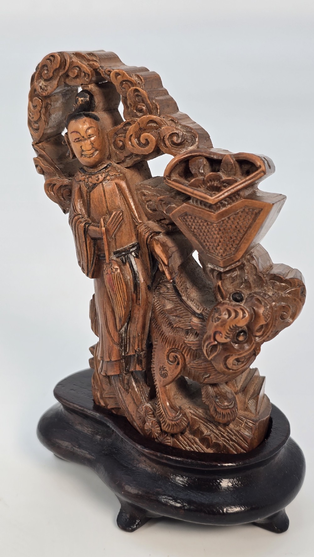 A Japanese carved bamboo okimono figure depicted beside a mythological beast on a dark carved hardwood base. View XI