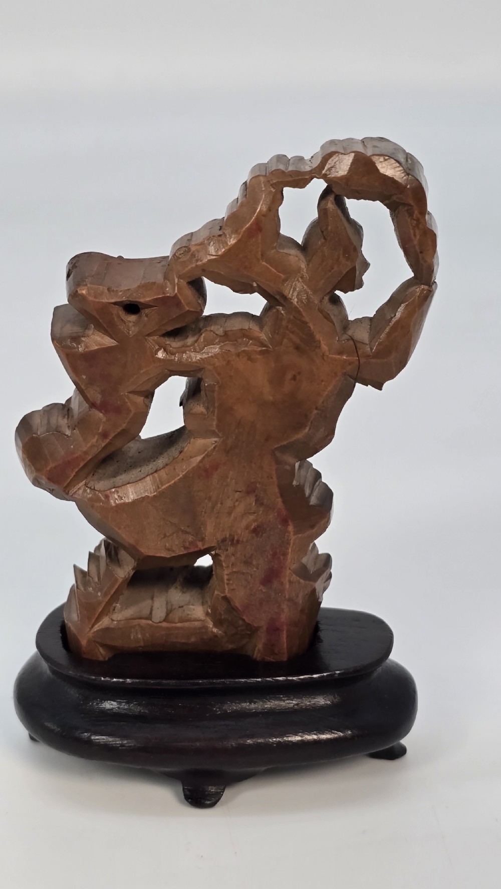 A Japanese carved bamboo okimono figure depicted beside a mythological beast on a dark carved hardwood base. View XVI