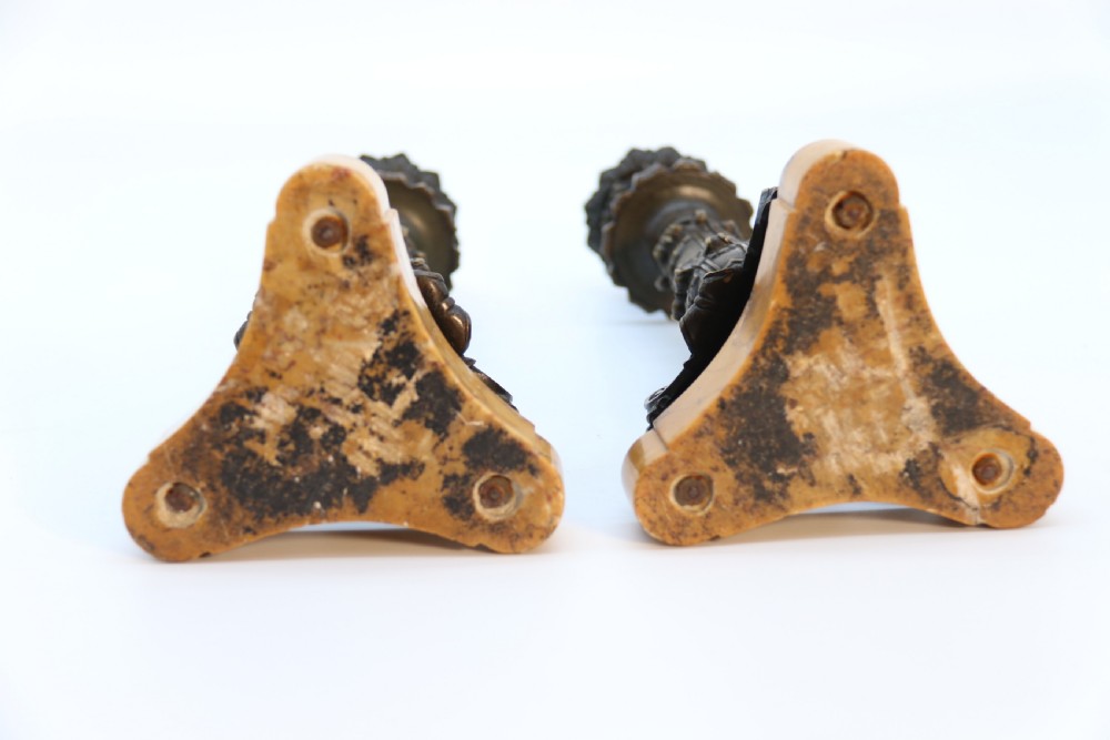 A pair of antique French Empire dark bronze candlesticks with ornate floral carvings and claw feet, resting upon yellow sienna marble plinths. View VIII