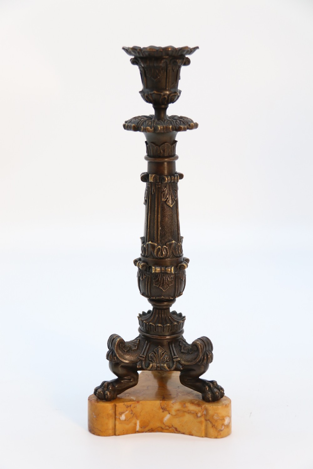A pair of antique French Empire dark bronze candlesticks with ornate floral carvings and claw feet, resting upon yellow sienna marble plinths. View IX