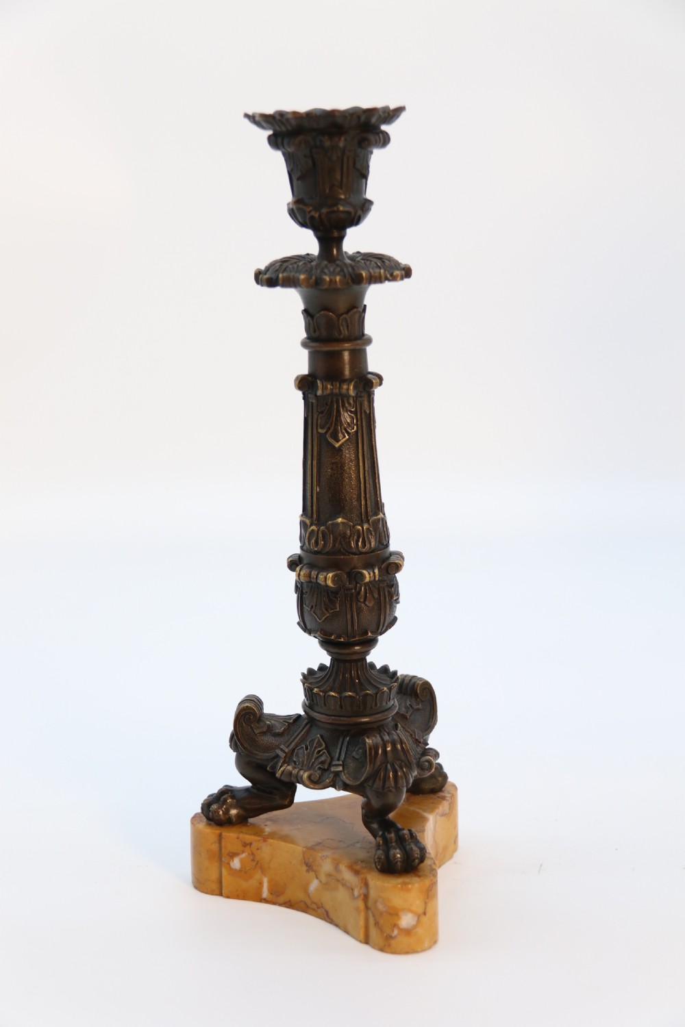 A pair of antique French Empire dark bronze candlesticks with ornate floral carvings and claw feet, resting upon yellow sienna marble plinths. View X