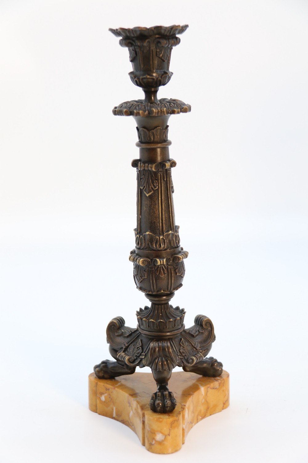 A pair of antique French Empire dark bronze candlesticks with ornate floral carvings and claw feet, resting upon yellow sienna marble plinths. View XI