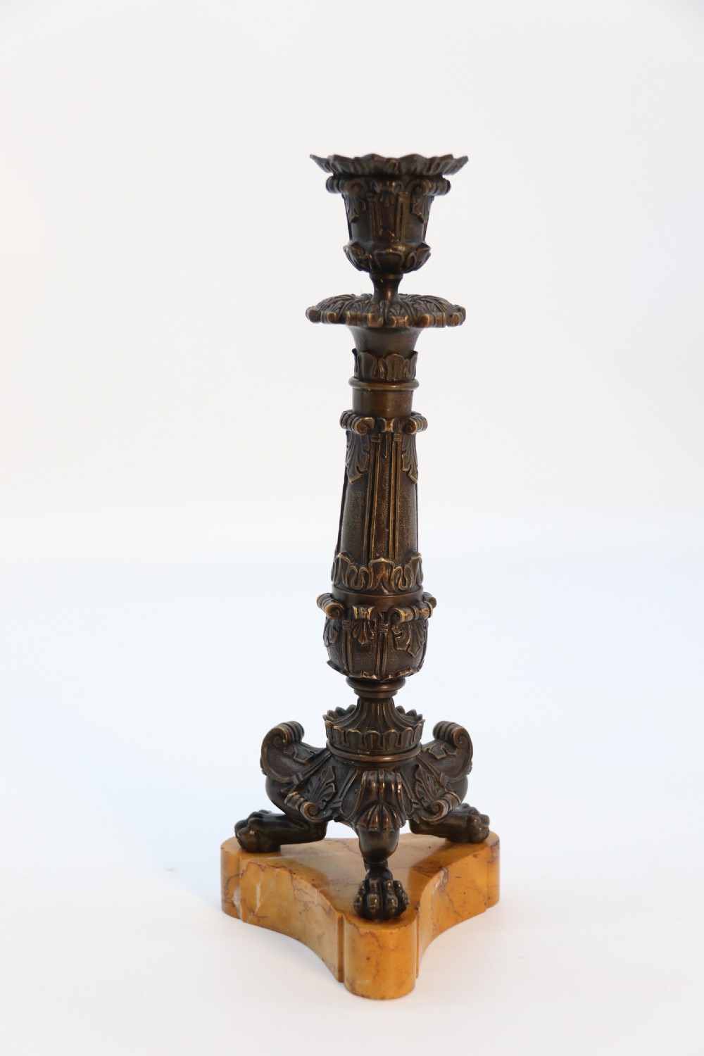 A pair of antique French Empire dark bronze candlesticks with ornate floral carvings and claw feet, resting upon yellow sienna marble plinths. View XIV