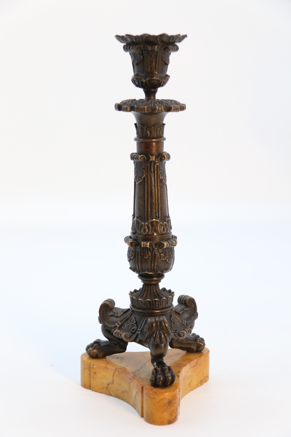 A pair of antique French Empire dark bronze candlesticks with ornate floral carvings and claw feet, resting upon yellow sienna marble plinths. View XVI