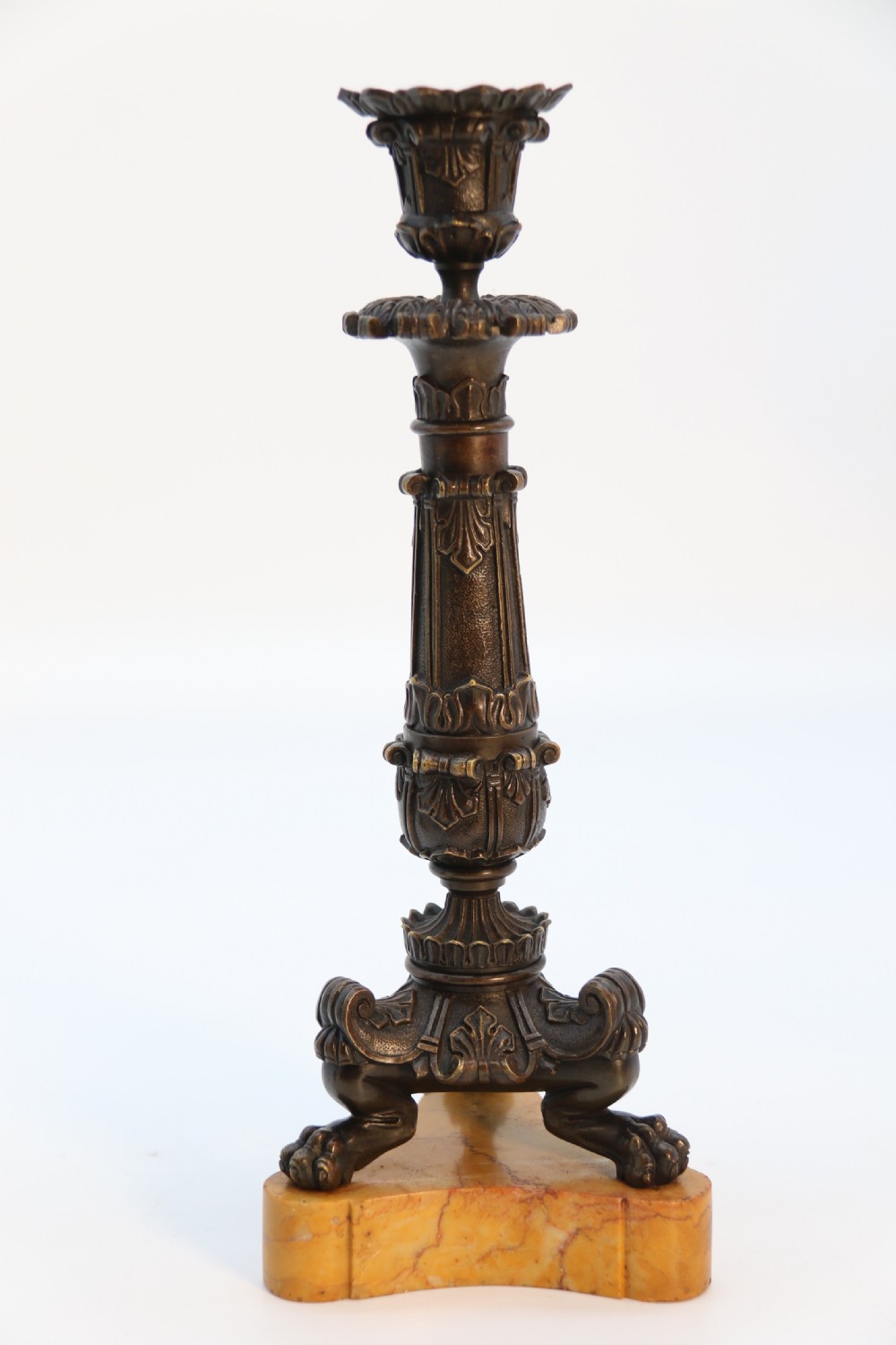 A pair of antique French Empire dark bronze candlesticks with ornate floral carvings and claw feet, resting upon yellow sienna marble plinths. View XVII