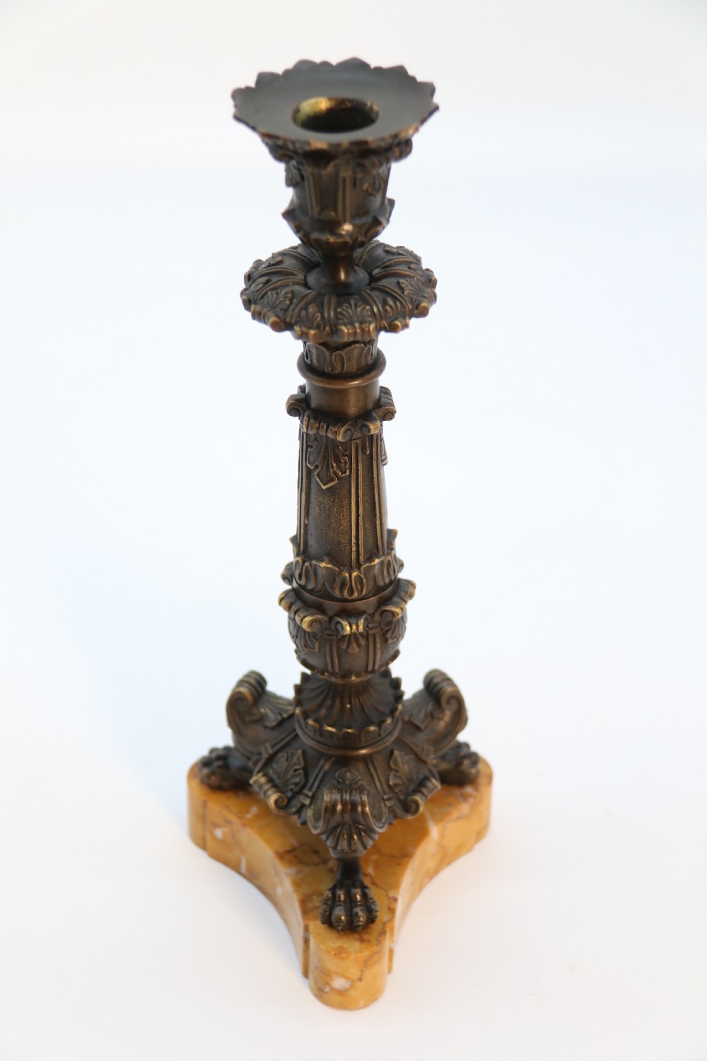 A pair of antique French Empire dark bronze candlesticks with ornate floral carvings and claw feet, resting upon yellow sienna marble plinths. View XIX