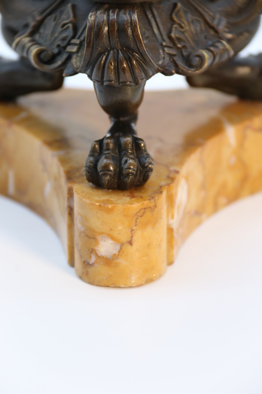 A pair of antique French Empire dark bronze candlesticks with ornate floral carvings and claw feet, resting upon yellow sienna marble plinths. View XX