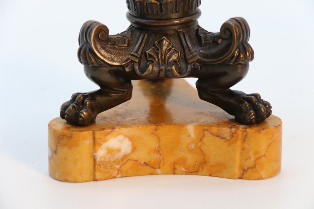 A pair of antique French Empire dark bronze candlesticks with ornate floral carvings and claw feet, resting upon yellow sienna marble plinths. View XXII