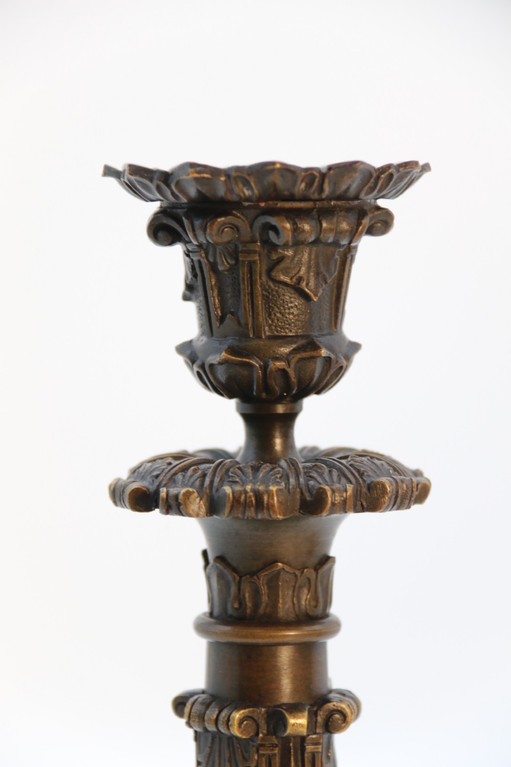 A pair of antique French Empire dark bronze candlesticks with ornate floral carvings and claw feet, resting upon yellow sienna marble plinths. View XXIII