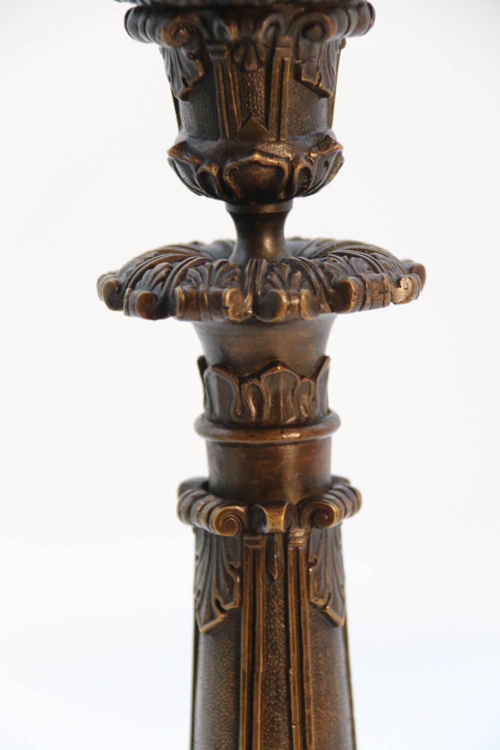 A pair of antique French Empire dark bronze candlesticks with ornate floral carvings and claw feet, resting upon yellow sienna marble plinths. View XXIV