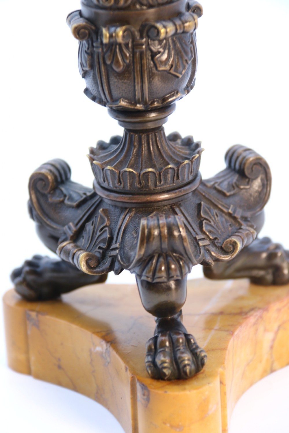 A pair of antique French Empire dark bronze candlesticks with ornate floral carvings and claw feet, resting upon yellow sienna marble plinths. View XXV