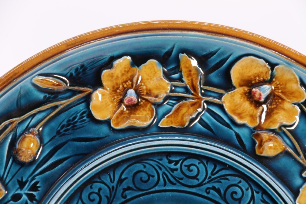 A circular late nineteenth-century Austrian majolica decorative plate featuring relief mouldings of birds perched on branches beside sunflowers over a teal glazed background. View IX