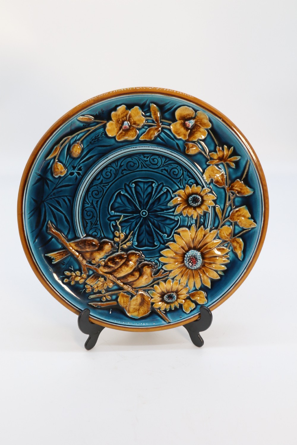 A circular late nineteenth-century Austrian majolica decorative plate featuring relief mouldings of birds perched on branches beside sunflowers over a teal glazed background. View XII
