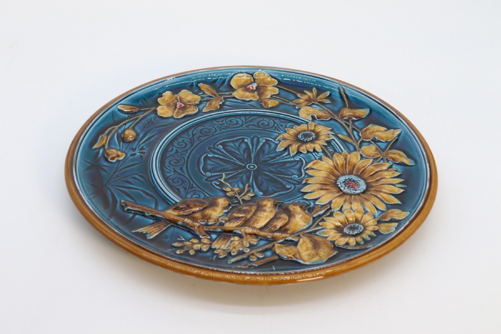 A circular late nineteenth-century Austrian majolica decorative plate featuring relief mouldings of birds perched on branches beside sunflowers over a teal glazed background. View XIV