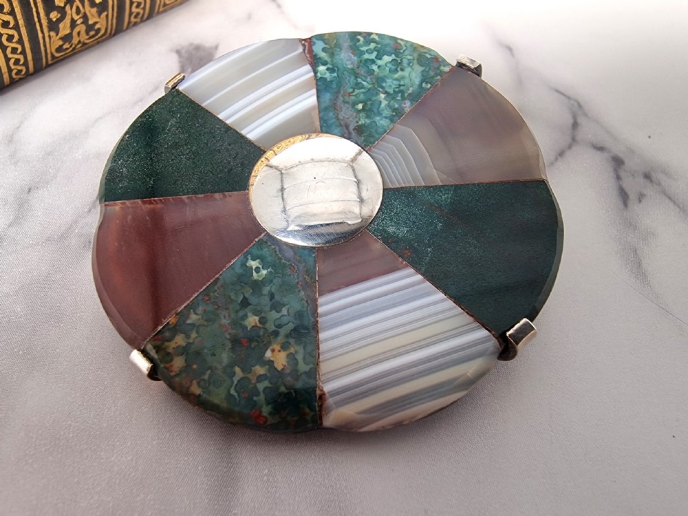 A late 19th-century circular Scottish silver brooch featuring segmented wedge inlays of varied banded agates and jaspers surrounding a central silver disc. View IV