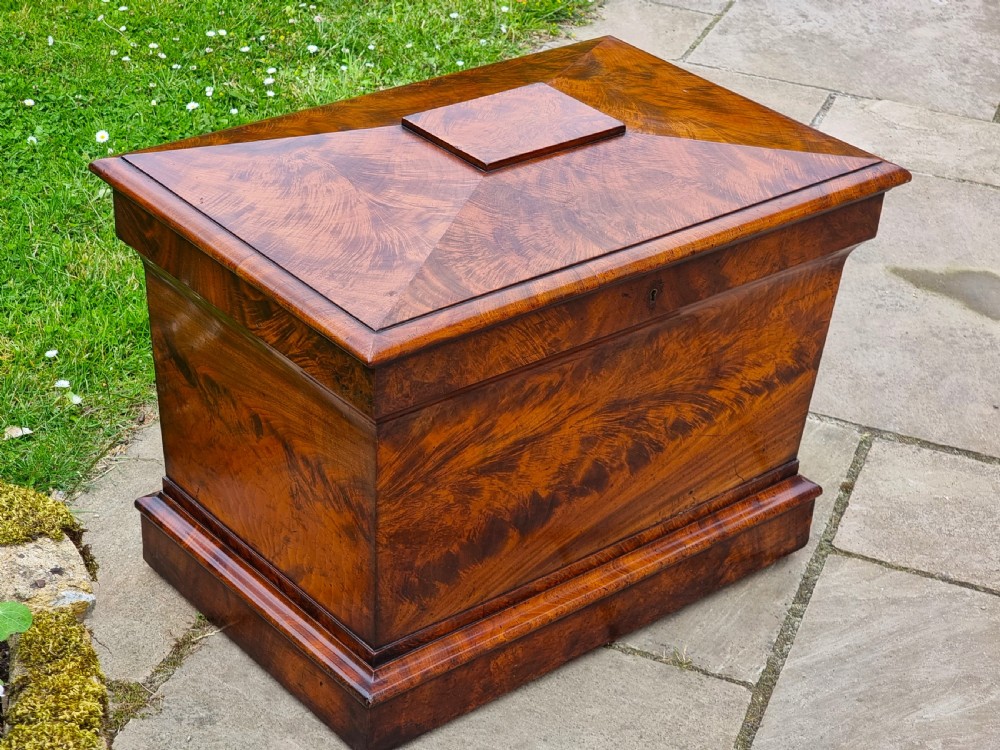 A Regency period sarcophagus-shaped wine cooler crafted from flame mahogany veneer with a stepped pediment lid and plinth base. View II