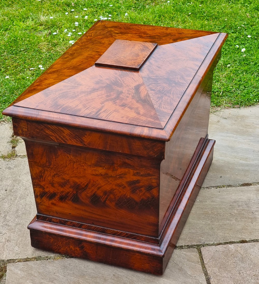 A Regency period sarcophagus-shaped wine cooler crafted from flame mahogany veneer with a stepped pediment lid and plinth base. View V