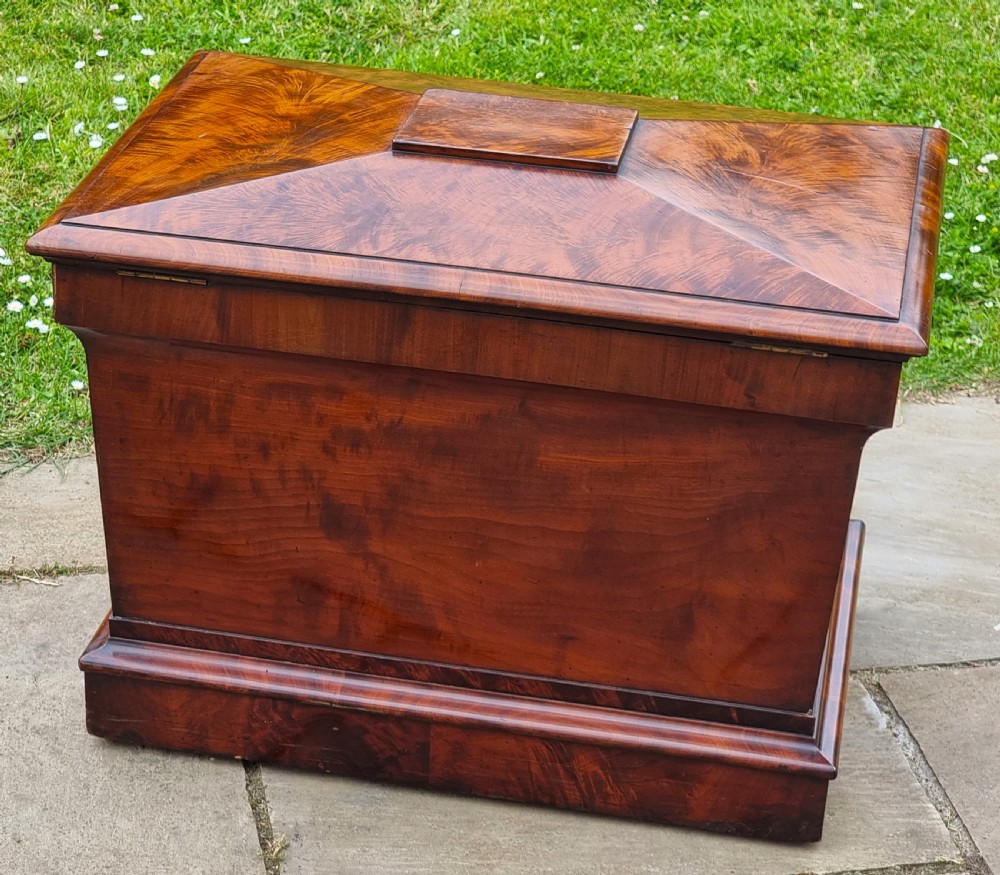 A Regency period sarcophagus-shaped wine cooler crafted from flame mahogany veneer with a stepped pediment lid and plinth base. View VI