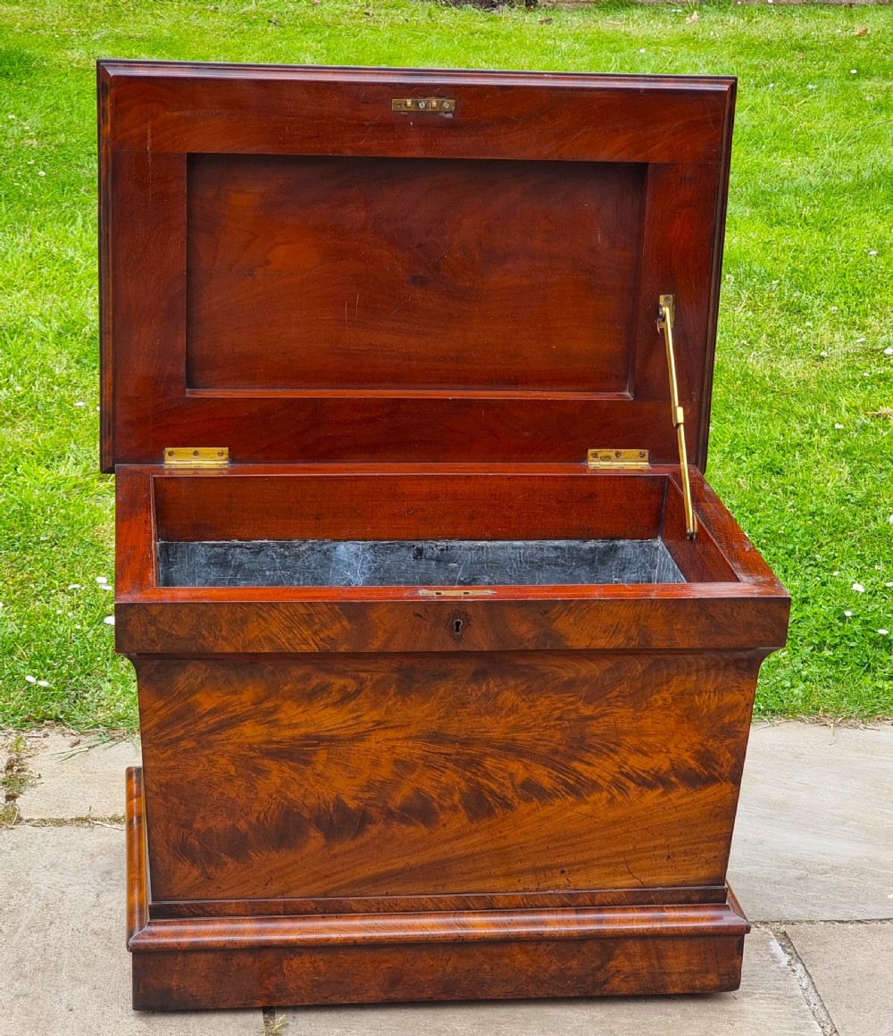 A Regency period sarcophagus-shaped wine cooler crafted from flame mahogany veneer with a stepped pediment lid and plinth base. View IX